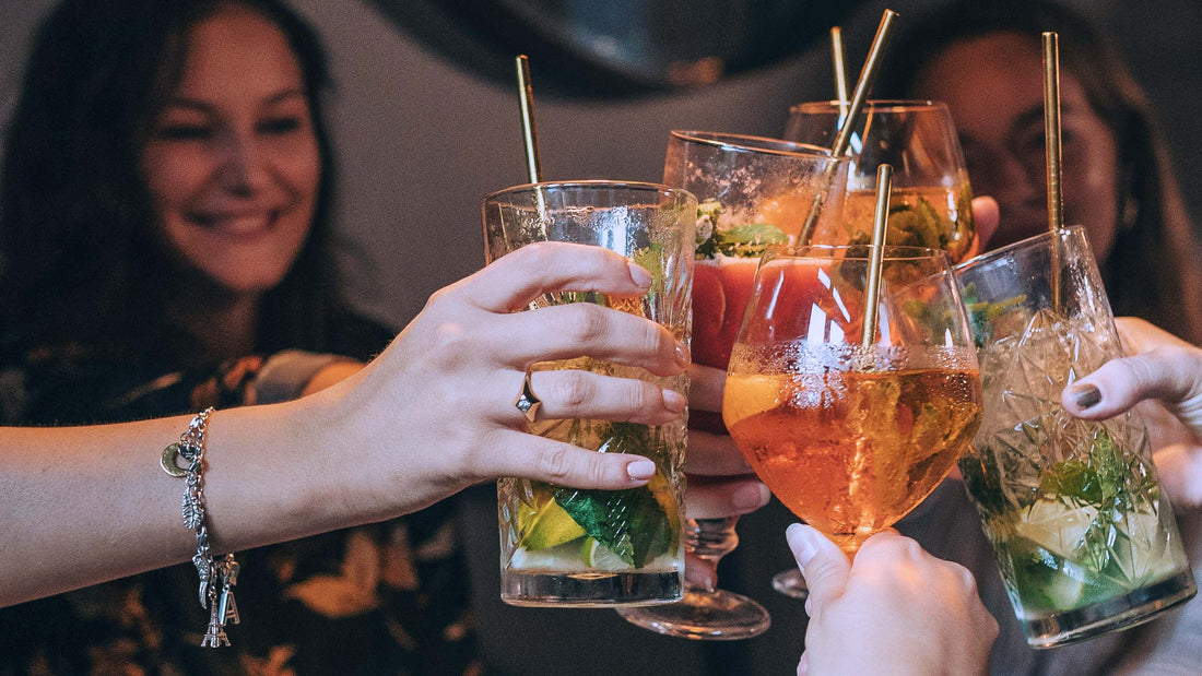 Women smiling and clinking cocktail glasses together, Cheers!