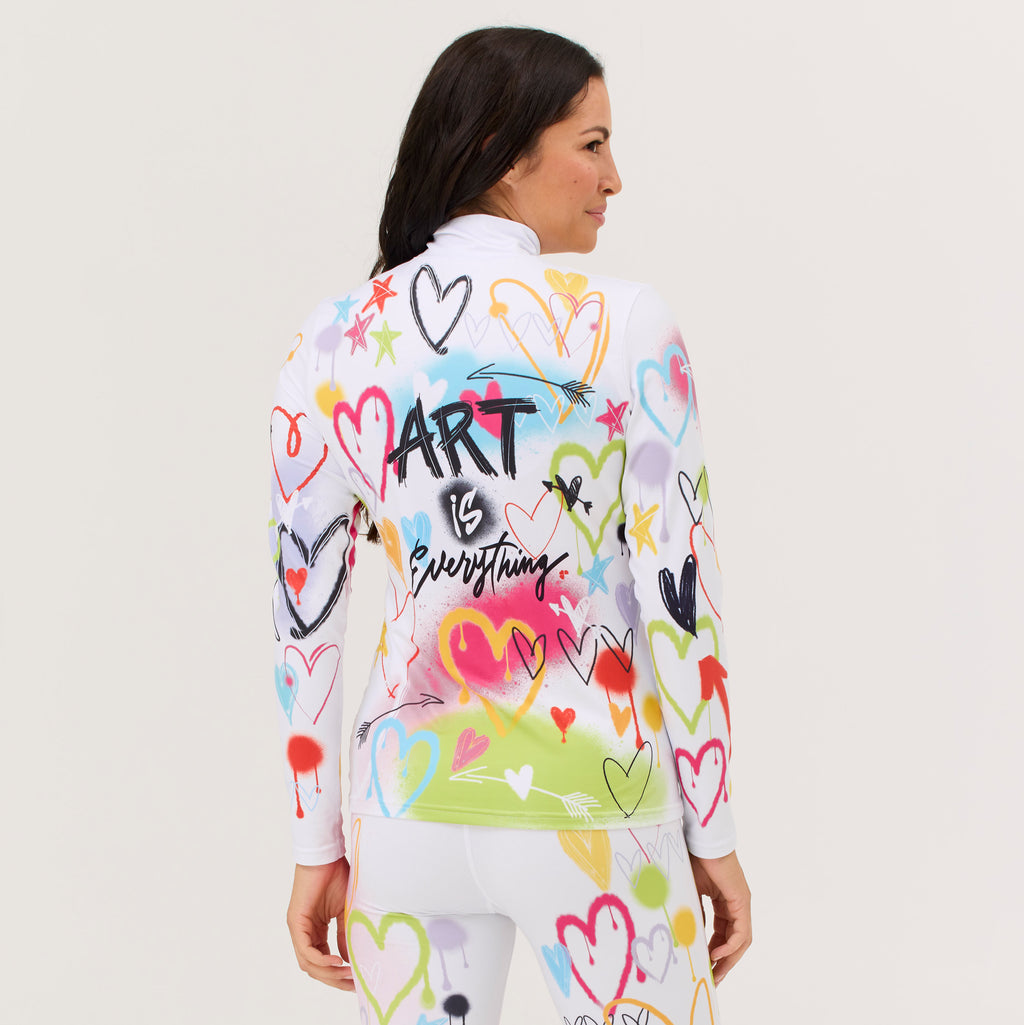 A woman shown from the back wearing a white long-sleeve athletic top and matching white leggings, both covered in colorful heart doodles and graffiti-style graphics. The back of the top features the text 'Art is Everything'.