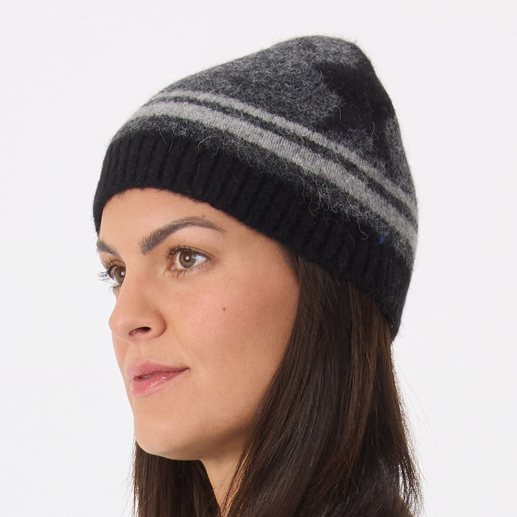 A woman wearing a dark gray and black knit beanie hat with two horizontal gray stripes and a black star, shown in profile against a plain light gray background.