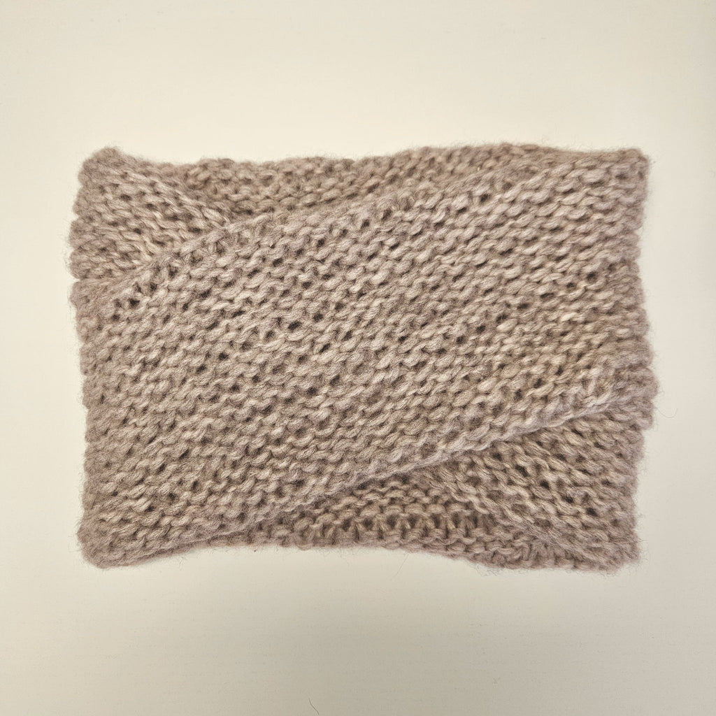 A chunky knit scarf in a taupe-beige color on a plain off-white background.